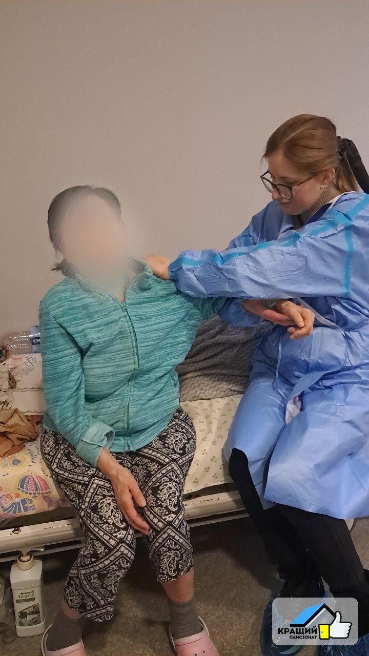 Реабілітолог навчає літнього чоловіка ходити з ходунками після виписки з лікарні у пансіонаті Кращий